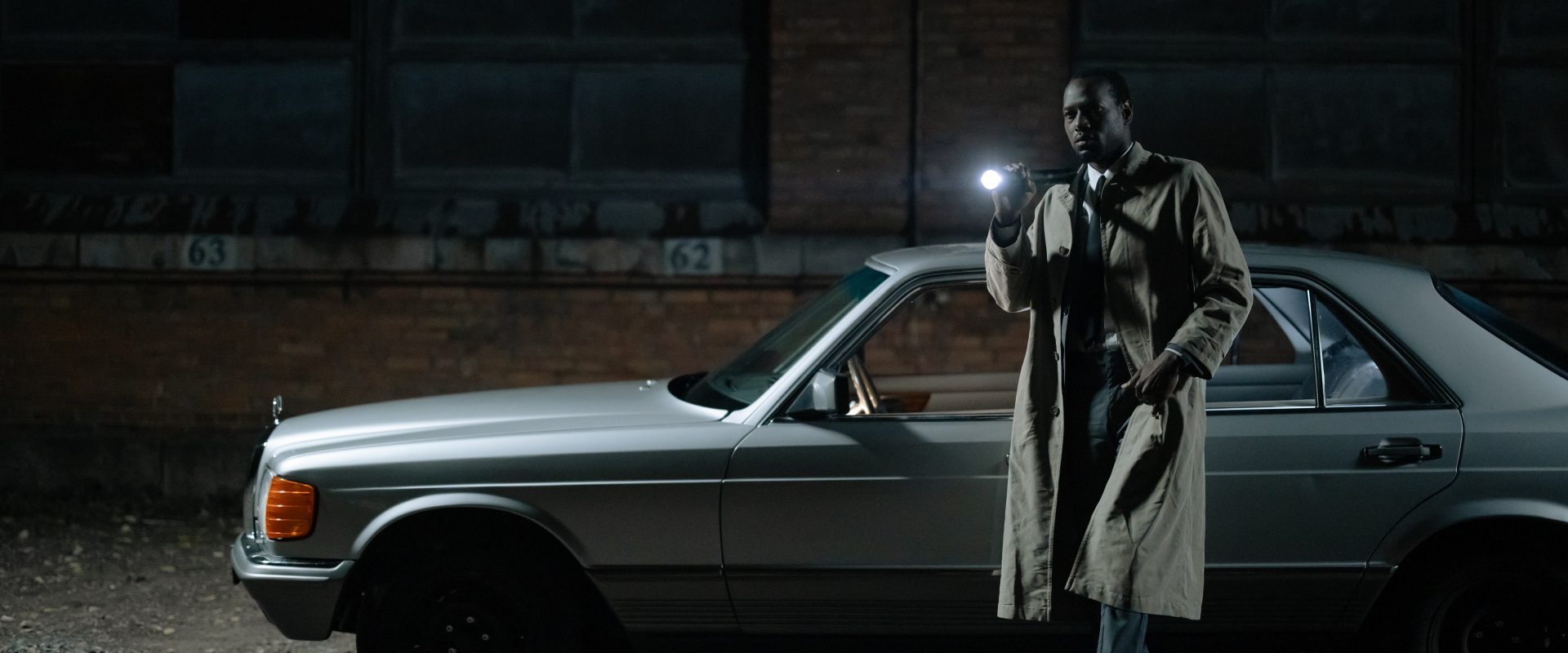 a man standing against a car with a torch